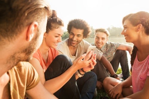 Young woman sharing content on her mobile phone with a group of friends